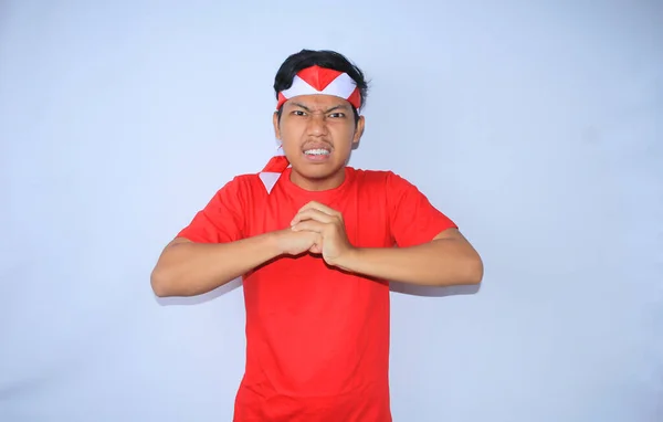 怒っているインドネシアの若者は インドネシア独立記念日に赤いTシャツとヘッドバンドを着て手を打つために手を挙げた — ストック写真
