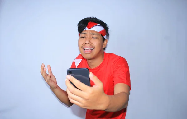 Trauriger Indonesischer Junger Mann Weint Beim Blick Auf Sein Smartphone — Stockfoto