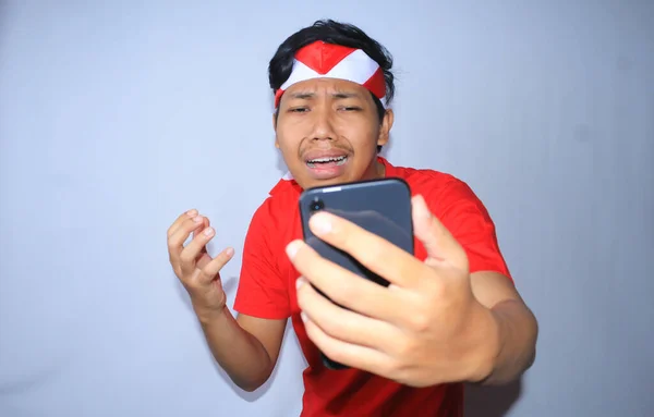 Грустный Индонезийский Молодой Человек Плачет Глядя Свой Смартфон Одетый Красную — стоковое фото