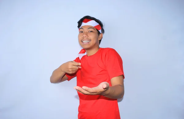 インドネシアの男性の肖像画 左手で微笑み 赤いTシャツとヘッドバンドを着て インドネシアの独立記念日を祝い カメラを見る — ストック写真