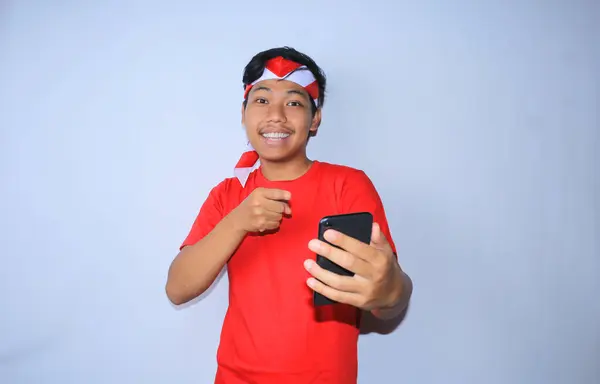 Gülümseyen Endonezyalı Genç Adam Mutlu Heyecanlı Yüzüyle Cep Telefonunu Işaret — Stok fotoğraf