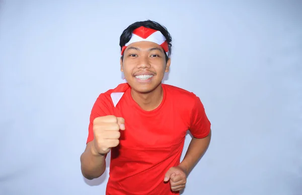 幸せなインドネシアの若い男は インドネシア独立記念日に赤いTシャツとヘッドバンドを着用割引を得るために笑顔でポーズを実行している白 — ストック写真