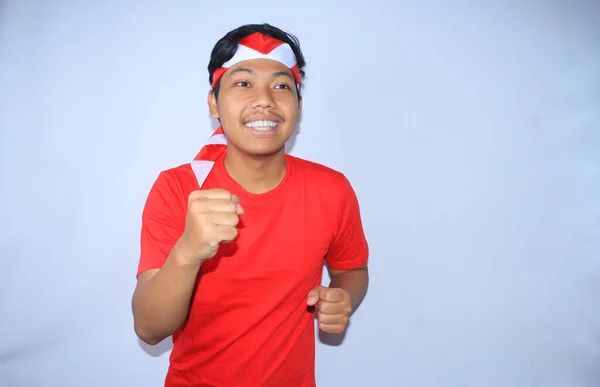 幸せなインドネシアの若い男は インドネシア独立記念日に赤いTシャツとヘッドバンドを着用割引を得るために笑顔でポーズを実行している白 — ストック写真