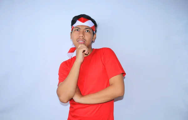思慮深いインドネシアの若者は インドネシア独立記念日に赤いTシャツとヘッドバンドを身に着けている中国の手で考え 疑う白 — ストック写真