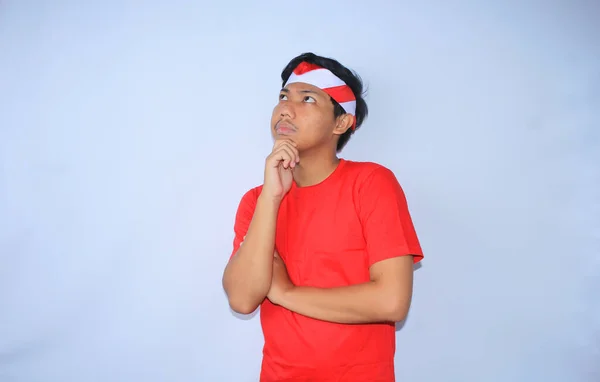 思慮深いインドネシアの若者は インドネシア独立記念日に赤いTシャツとヘッドバンドを身に着けている中国の手で考え 疑う白 — ストック写真