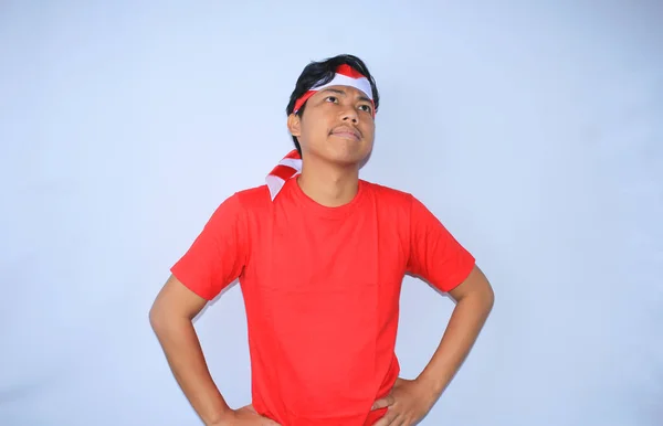호기심 인도네시아 남자는 허리에 손으로 생각하고 빨간색 티셔츠와 인도네시아 밴드를 — 스톡 사진