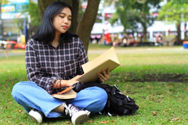 Genç bayan Asyalı öğrenci sınava hazırlanmak için ciddi ciddi bir not defteri okudu.