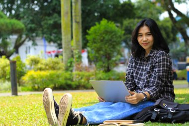 Uzaktan kumandayla çalışan neşeli Asyalı kadın, video görüşmesi ve kameraya bakan kitap okumak.