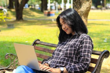 Sakin ol Asyalı genç bayan. Laptop kullanarak gülümse. Serbest çalış ve mutlu ol.