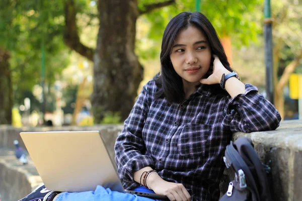 happy young woman asian smile enjoy working on laptop with satisfied expression in outdoors work area