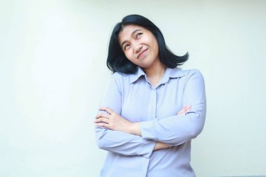 Çekici, güzel Asyalı genç bir kadın kollarını katlayarak yukarı bakıyor hayal gücünü düşünerek izole edilmiş bir takım elbise giyiyor.