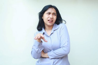 Tatmin olmamış Asyalı genç iş kadını elini kaldırıyor ve omuz silkiyor. Beyaz arka plandaki boş alana bakıyor.