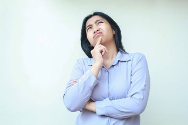 Güzel Asyalı iş kadını, elleri çenesinde ve kolları katlanmış bir şekilde beyaz arka planda izole edilmiş resmi bir gömlek giyer.