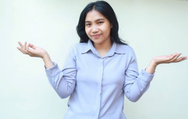 Mutlu yüzüyle kameraya bakan barışçıl Asyalı kadın avuç içi jest yapar, hayali ürünü göz önünde bulundurur, beyaz arka planda izole edilmiş resmi tişört giyer,