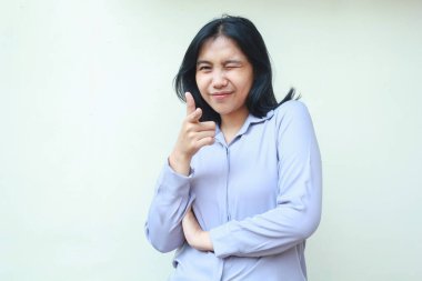 Mutlu Asyalı genç iş kadını göz kırp ve kameraya başparmağınla işaret et izole edilmiş beyaz arka plan üzerinde ayakta duran kendine güvenen, resmi gömlek giy.