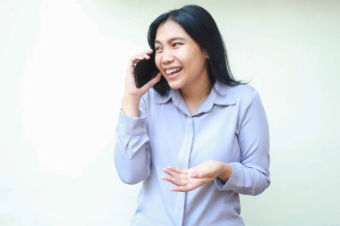 Mutlu Asyalı genç iş kadınının görüntüsü. Neşeli bir gülüşle mafya telefonuyla konuşmaktan zevk alıyor. Mor gömlekli.