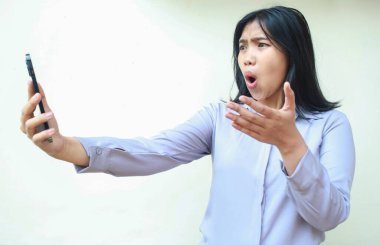 Güzel Asyalı genç iş kadını el ele tutuşup el ele tutuşurken, el ele tutuşurken, jestleri sorgularken, resmi gömlekler giyerken, izole beyaz arka planda dikilirken şok geçirdi.