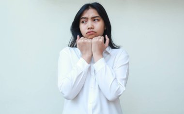 Stüdyoda hayal kırıklığına uğramış Asyalı genç iş kadını yöneticisinin beyaz takım elbise giymiş, ayakta duran, kasvetli yüz ifadesini takınarak çenesini kaldırmayı düşünmesi.