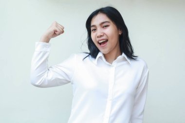 Güçlü Asyalı iş kadını menajeri yumruğunu kaldırıyor beyaz gömlekli, resmi takım elbiseli beyaz arka planda izole kameraya bakıyor.