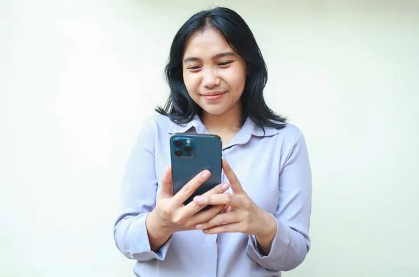 Barışçıl Asyalı genç iş kadını akıllı telefon uygulaması, çevrimiçi alışveriş ve sosyal medya kullanmaktan hoşlanır, sanal ortamda sörf yapmaktan heyecan duyar, izole beyaz arka planda duran resmi gömlekler giyer, ekrana bakın.