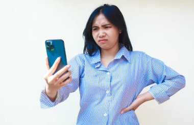 Mavi çizgili gömlek giyen, cep telefonu tutan, avuçlarını kaldıran Asyalı kızgın kadın izole beyaz arka planda dikiliyor.