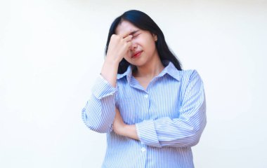 depresif Asyalı kadının başı ağrıyor mavi çizgili gömlek giyiyor kollarını katlayarak burnuna dokunuyor izole arka planda duruyor