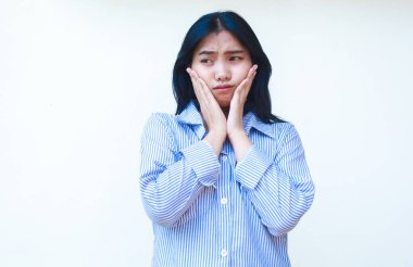 depresif Asyalı kadın üzgün mavi çizgili gömlek giyiyor yanağına dokunuyor izole arka planda duruyor