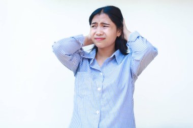 Asyalı stresli kadın mavi çizgili tişört giyiyor. Suratı asık. İzole edilmiş beyaz arka planda duruyor.