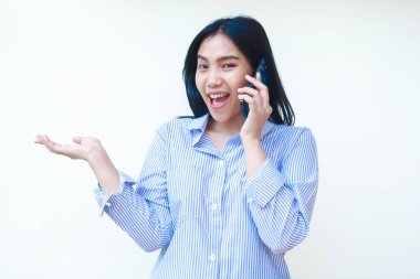 Heyecanlı Asyalı kadın akıllı telefondan konuşuyor ve işaret ediyor. Beyaz arka planda izole edilmiş çizgili gömlek giyiyor.