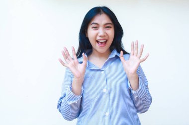 Mutlu Asyalı kadın, izole edilmiş beyaz arka planda duran çizgili gömlekli kameraya bakarken şok oldu.