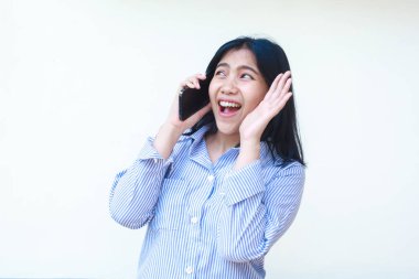 Mutlu Asyalı kadın cep telefonuyla konuşurken şaşırdı. Beyaz arka planda izole edilmiş çizgili gömlek giyiyordu.