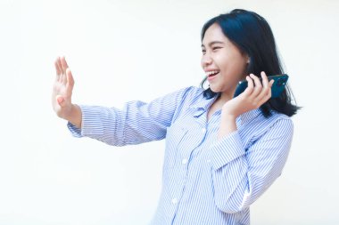 Mutlu Asyalı kadın cep telefonuyla konuşurken şaşırdı. Beyaz arka planda izole edilmiş çizgili gömlek giyiyordu.