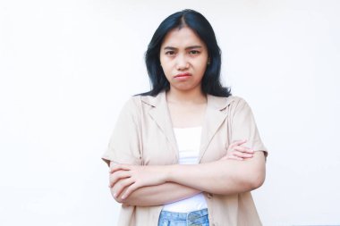 Asyalı kızgın kadın cehaletle kollarını kavuşturuyor. Beyaz arka planda izole edilmiş günlük kıyafetler giyiyor.