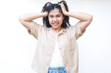 Kafası karışmış Asyalı kadın kendini stresli ve bunalmış hissediyor. Beyaz arka planda izole edilmiş günlük kıyafetler giyiyor.