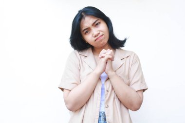 Düşünceli Asyalı kadın dua etmek ve umut etmek için el ele tutuşup beyaz arka planda izole edilmiş günlük giysiler giyiyor.