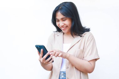 Akıllı telefon gülüşü kullanan heyecanlı Asyalı kadın beyaz arka planda izole edilmiş sosyal medyanın tadını çıkarıyor