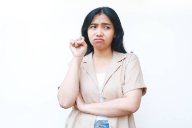 Üzgün Asyalı kadın ağlıyordu. Mutsuz hissediyordu. Beyaz arka planda, günlük kahverengi kıyafetler giyiyordu.