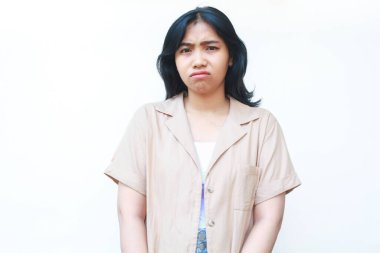 Üzgün Asyalı kadın ağlıyordu. Mutsuz hissediyordu. Beyaz arka planda, günlük kahverengi kıyafetler giyiyordu.