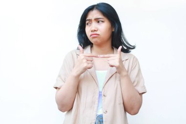 Üzgün Asyalı kadın ağlıyordu. Mutsuz hissediyordu. Beyaz arka planda, günlük kahverengi kıyafetler giyiyordu.