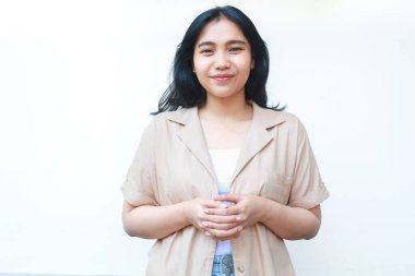 Mutlu sakin Asyalı kadın gülümsüyor beyaz arka planda izole edilmiş günlük kahverengi kıyafetler giyiyor.