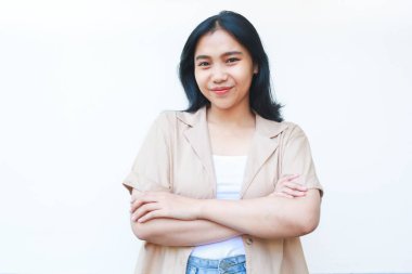 Mutlu barışçıl Asyalı kadın kameraya özgüvenle bakıyor ve beyaz arka planda izole edilmiş günlük kahverengi kıyafetler giyiyor.