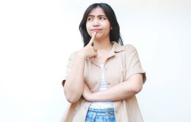 Düşünceli Asyalı kadın beyaz arka planda izole edilmiş günlük kahverengi kıyafetler giyiyor.