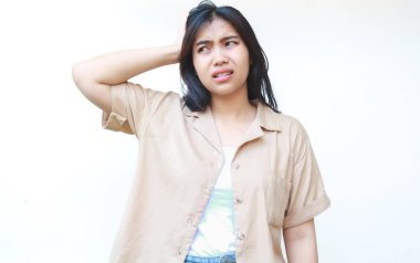 Düşünceli Asyalı kadın beyaz arka planda izole edilmiş günlük kahverengi kıyafetler giyiyor.