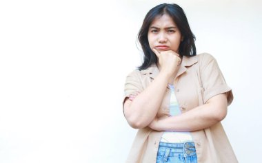 Düşünceli Asyalı kadın beyaz arka planda izole edilmiş günlük kahverengi kıyafetler giyiyor.