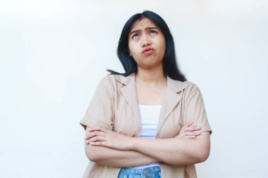 Düşünceli Asyalı kadın beyaz arka planda izole edilmiş günlük kahverengi kıyafetler giyerek ciddi ciddi düşünüyor.