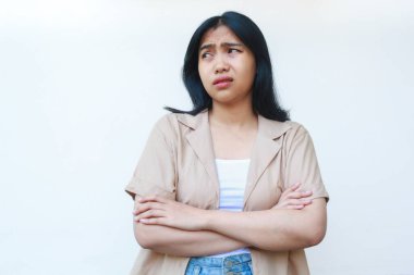 Düşünceli Asyalı kadın beyaz arka planda izole edilmiş günlük kahverengi kıyafetler giyerek ciddi ciddi düşünüyor.