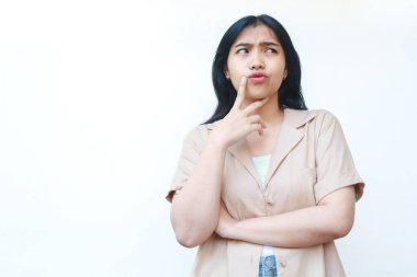 Düşünceli Asyalı kadın beyaz arka planda izole edilmiş günlük kahverengi kıyafetler giyiyor.