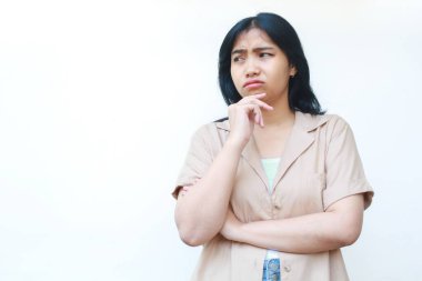 Düşünceli Asyalı kadın beyaz arka planda izole edilmiş günlük kahverengi kıyafetler giyiyor.