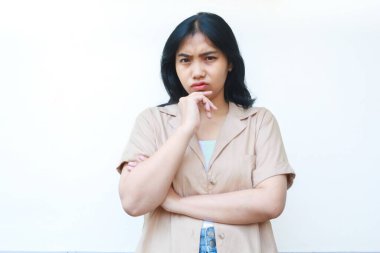 Düşünceli Asyalı kadın beyaz arka planda izole edilmiş günlük kahverengi kıyafetler giyiyor.