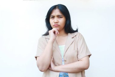 Düşünceli Asyalı kadın beyaz arka planda izole edilmiş günlük kahverengi kıyafetler giyiyor.